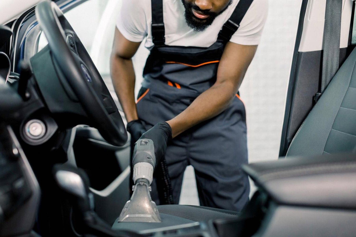 Technician vacuuming a car seat with a professional extractor in a UAE detailing studio